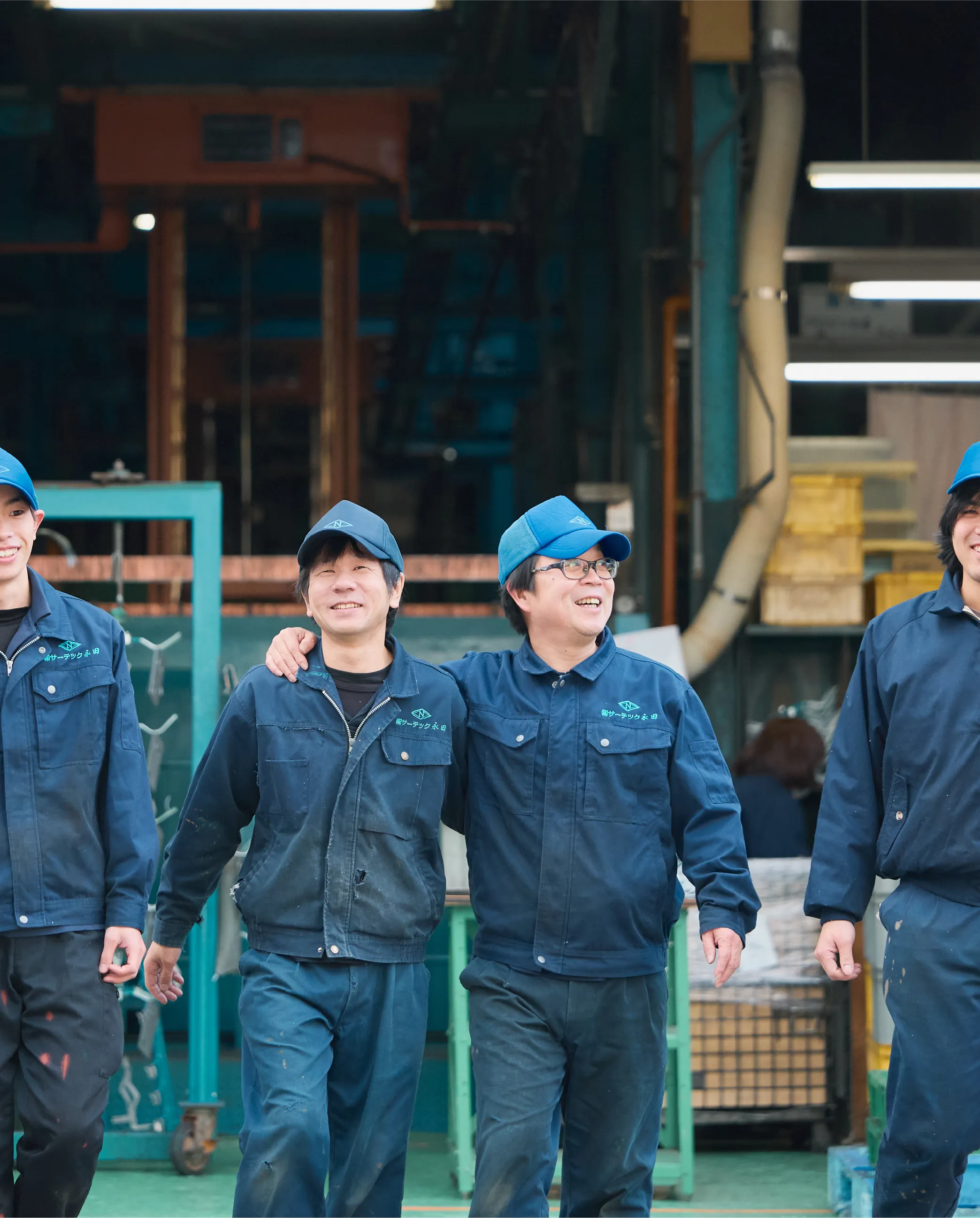 作業服を着た男性4人が横並びで歩く様子