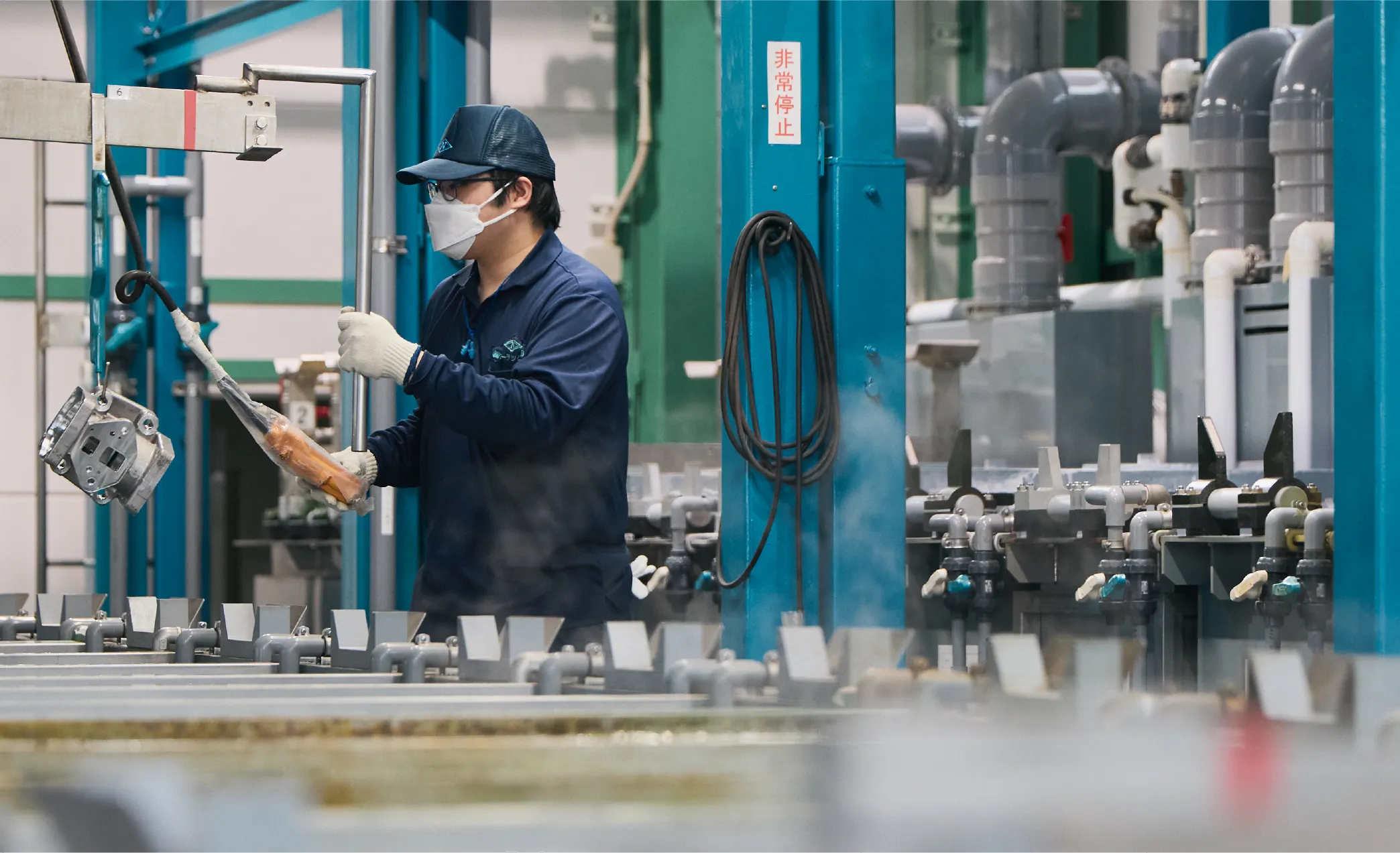 作業員を着た男性が2人の男性に説明を行う様子